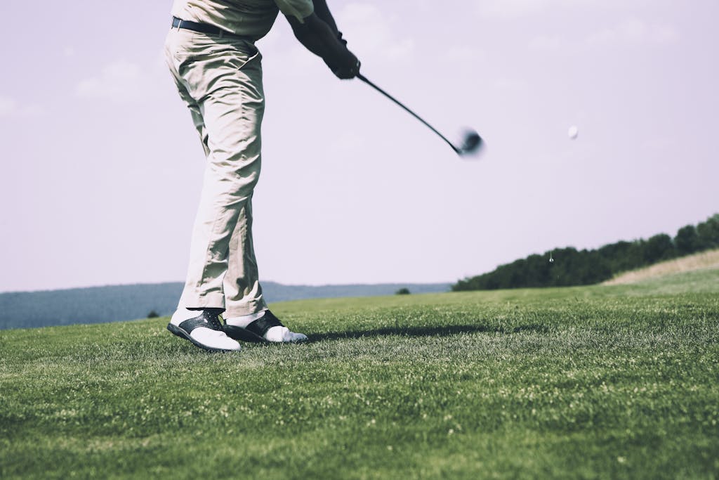 9 Complete Guide to a Perfect Golf Swing: Techniques, Tips, and Drills for Every Golfer 3 A golfer in mid-swing on a sunny day at the golf course, showing motion and focus.